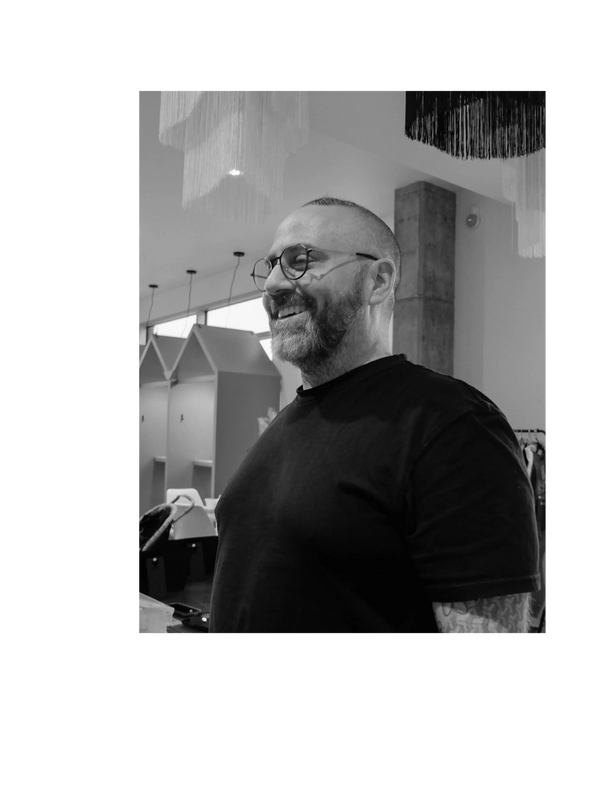 Smiling man with glasses and beard in a modern indoor setting.