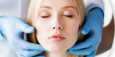 hygienist wearing blue medical gloves, feeling the neck and jawline of patient with closed eyes