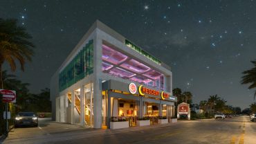 Modern two-story cheeseburger restaurant at night under a starry sky.