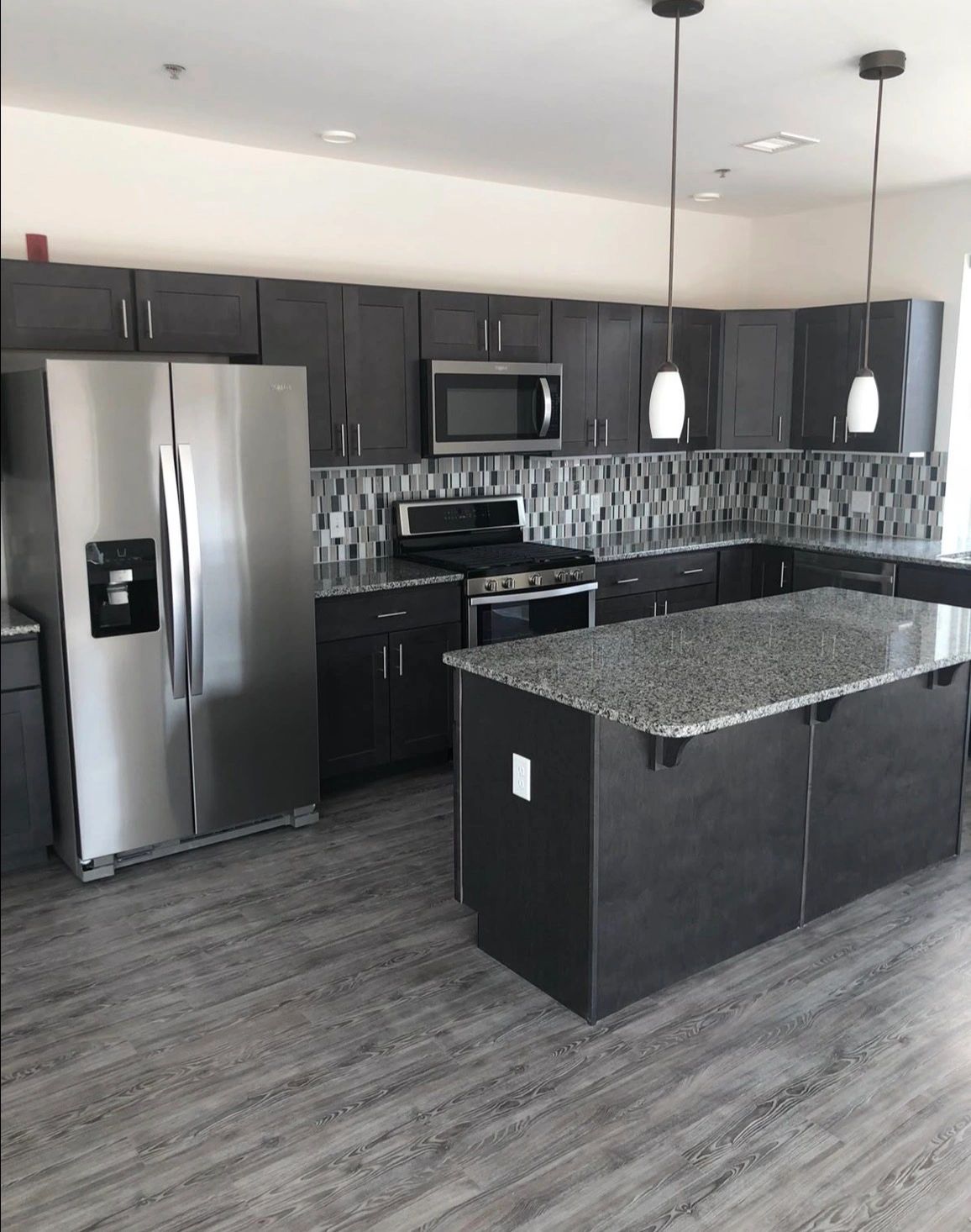 Modern kitchen with dark cabinets, stainless steel appliances, and granite countertops.