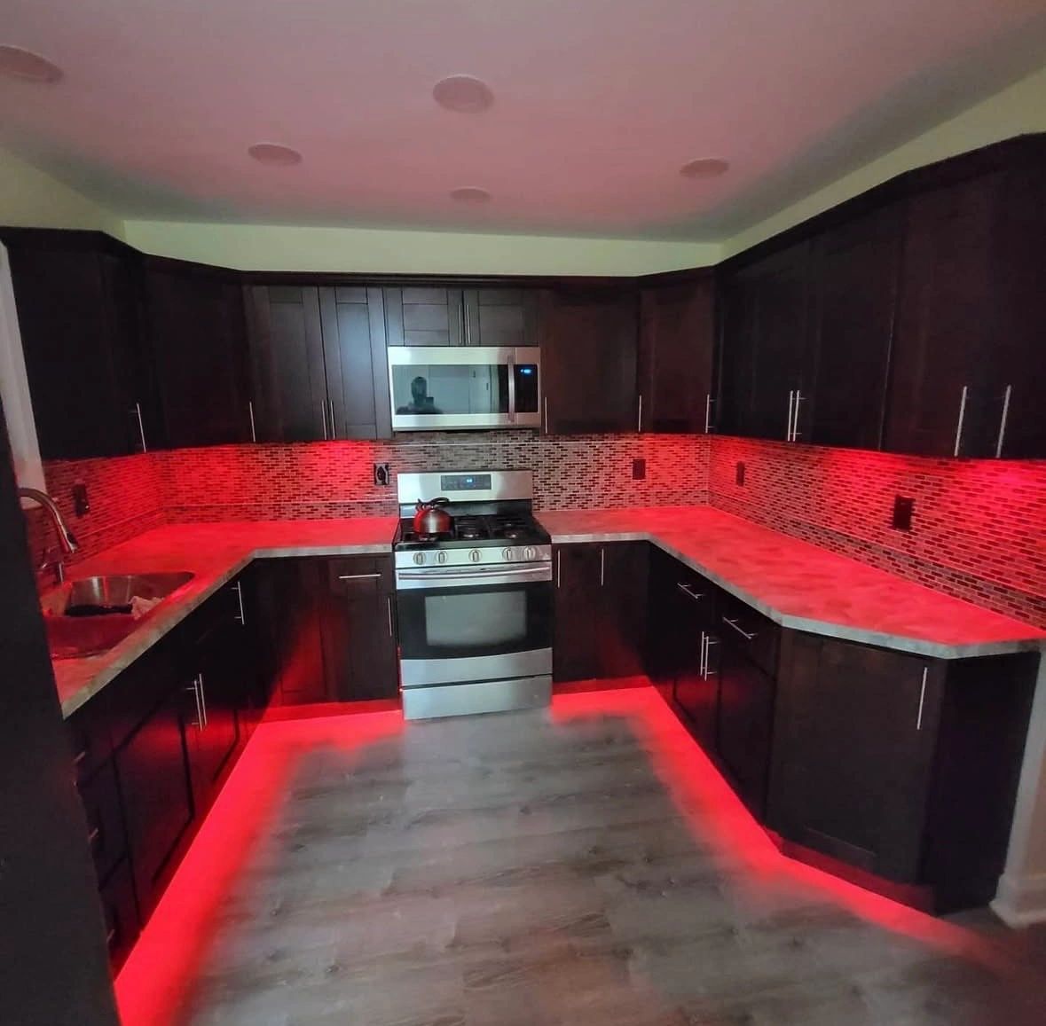 Modern kitchen with red LED under-cabinet and floor lighting.