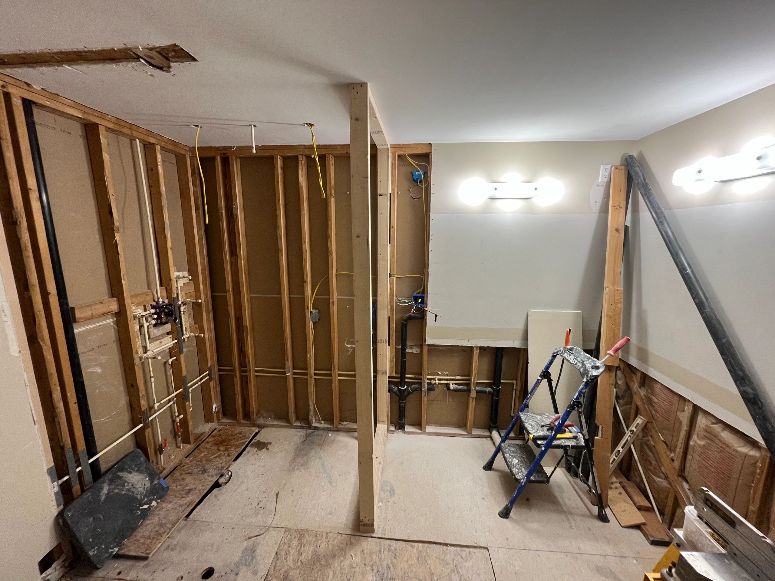 Room under renovation with exposed wall studs and construction tools.