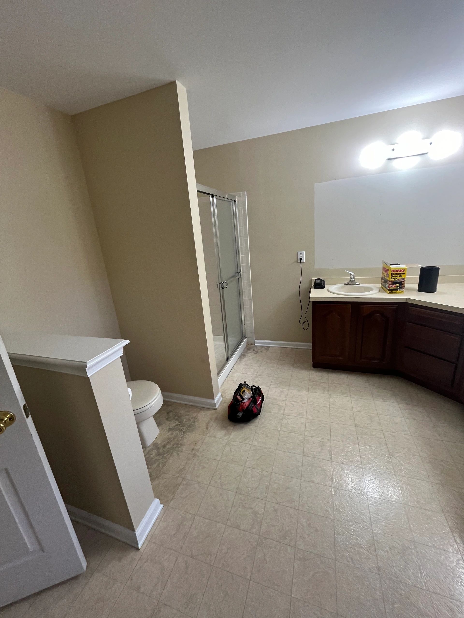 Bathroom with shower, toilet, sink, and tools on the floor.