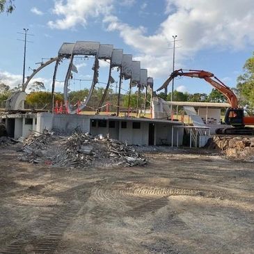 Demolition of a building with exposed steel arches and debris pile.