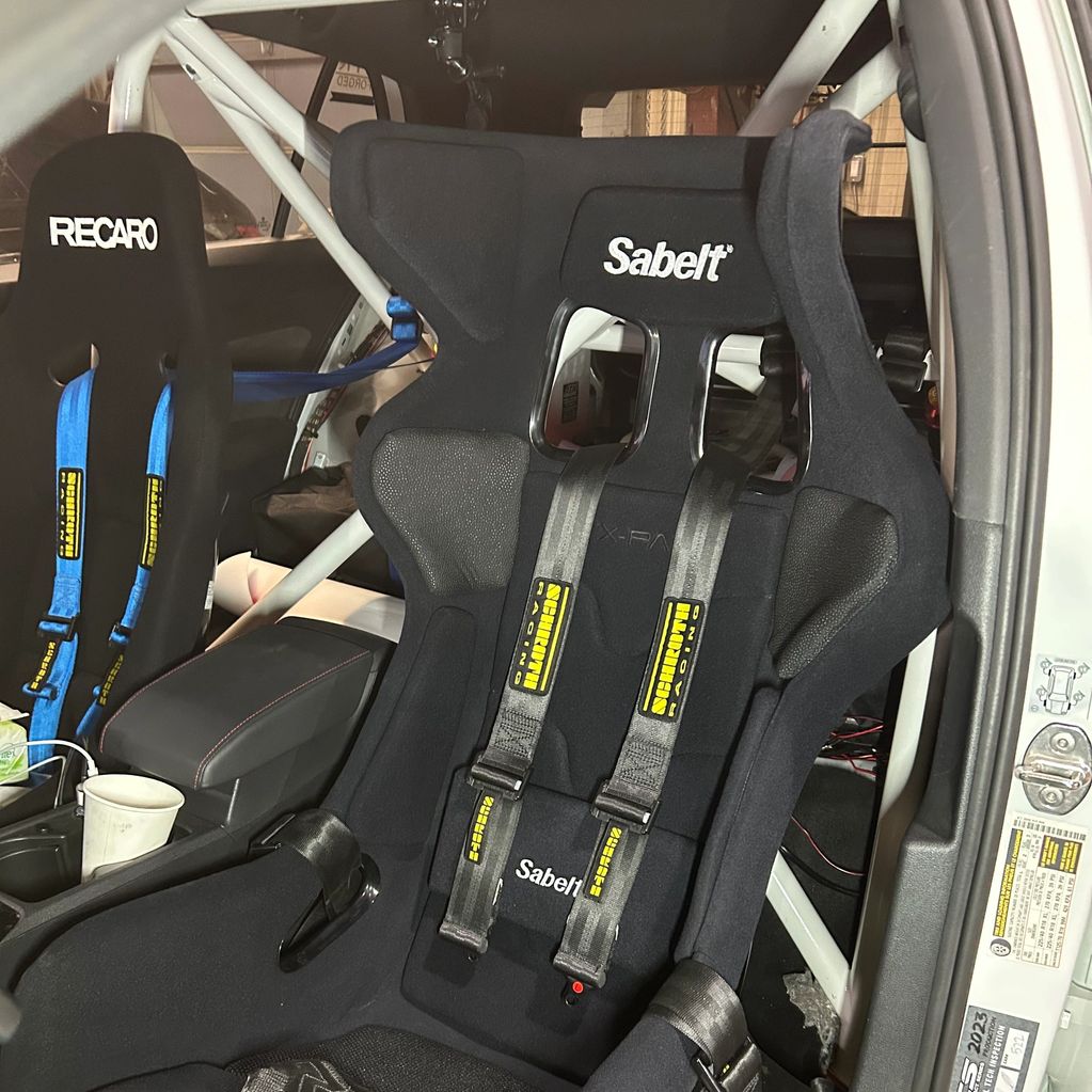 Racing seats by Sabelt and Recaro with harnesses inside a race car.