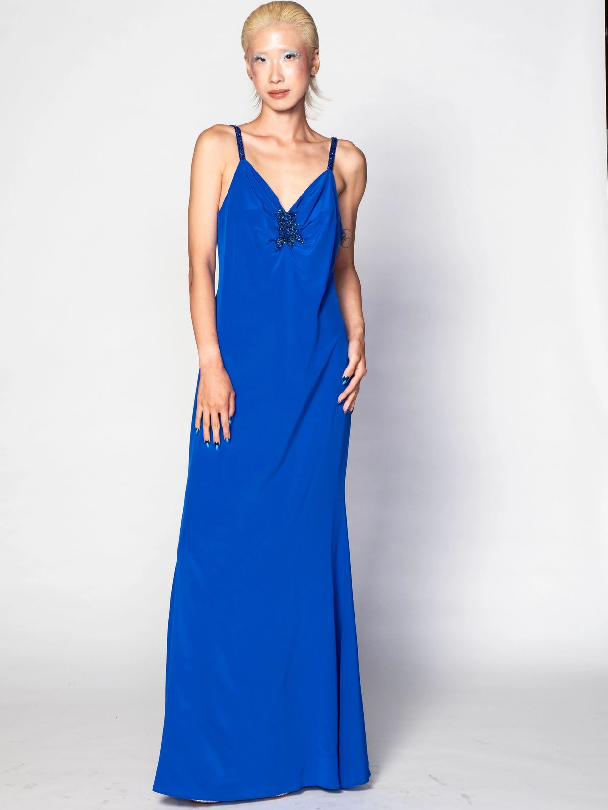 Model in a striking royal blue gown with intricate shoulder details.