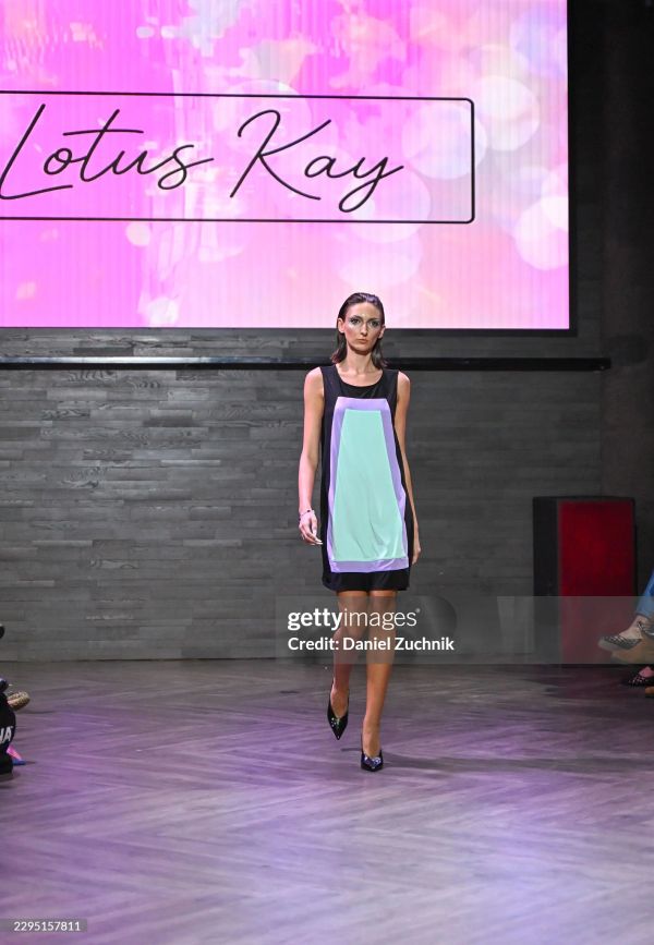 Model walking runway in a black and pastel color-block dress.