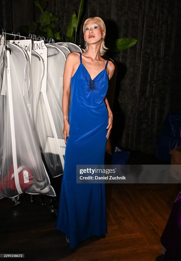 Model in a striking blue gown posing backstage.