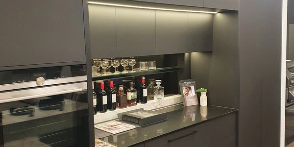 Modern kitchen bar area with wine bottles and glassware.