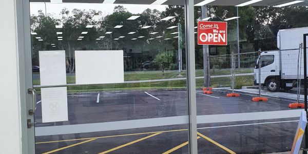 Glass door with an open sign and empty parking lot outside.