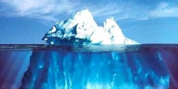 An iceberg with a small visible tip and a large submerged base under the water.