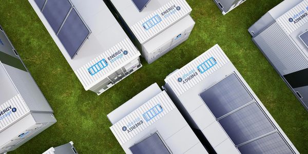 Aerial view of energy storage units with solar panels on grass.