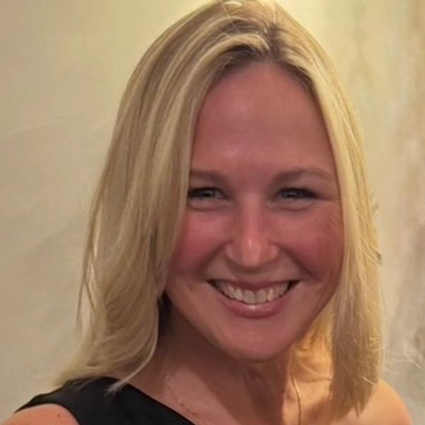 Smiling woman with blonde hair in a black one-shoulder dress.