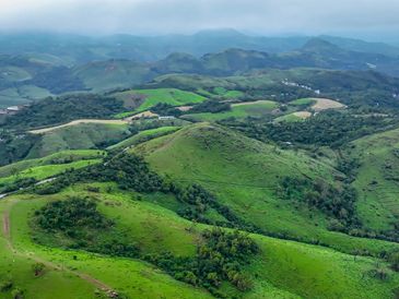 Aerial view of lush green hills under a cloudy sky.