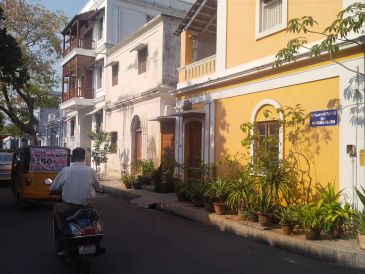 Man riding scooter on quiet street with colorful buildings.