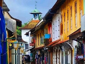 Colorful narrow street with shops and a clock tower.