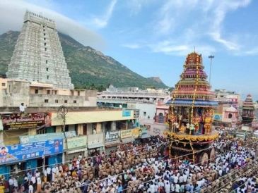 Large crowd gathers for festival near temple with mountain backdrop.