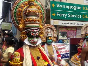 Traditional Kathakali performers in elaborate costumes on a street.