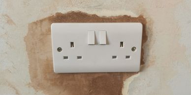 A double electrical outlet with switches on a stained wall.