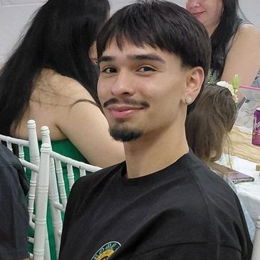 A young man with a goatee smiling at a social event.
