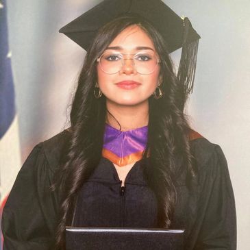 Young woman in graduation attire holding diploma, smiling confidently.