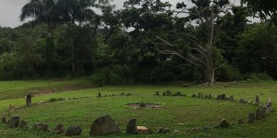 Stone circle on grassy field with trees.