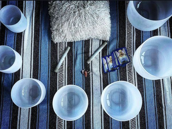Crystal singing bowls arranged on a striped cloth with a cushion and cards.