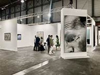 People viewing art in a spacious gallery with large portraits.