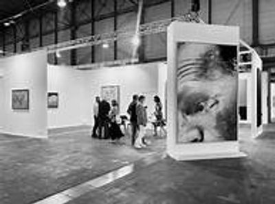 People viewing art in a spacious gallery with large portraits.
