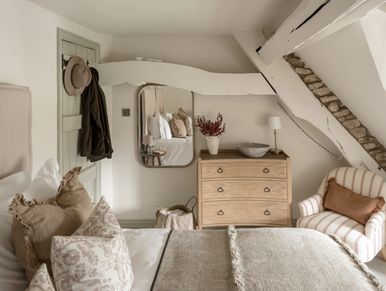 Cozy rustic bedroom with neutral tones and wooden furniture.
