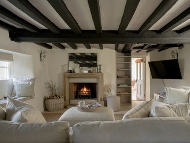 Cozy living room with a fireplace and rustic wooden beams.