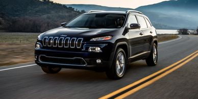 Black Jeep SUV driving on a road.