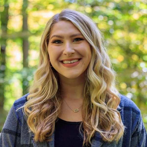 Smiling woman with long blonde hair outdoors.
