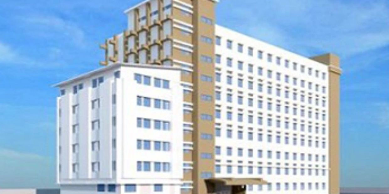 Modern multi-story building with a white and beige facade under a clear blue sky.