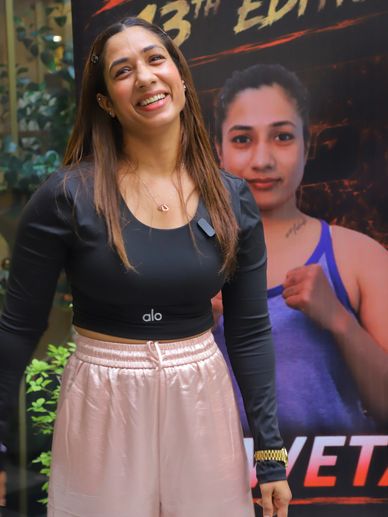 Woman smiling in front of a promotional poster.
