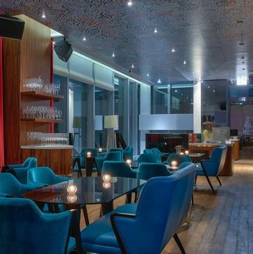 Modern bar with blue velvet chairs and ambient candle lighting. Perfect place for wine events.