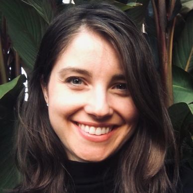 Smiling woman with long dark hair and green eyes.