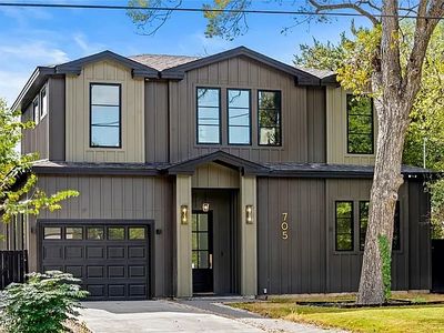 Modern two-story house with dark vertical siding and large windows.