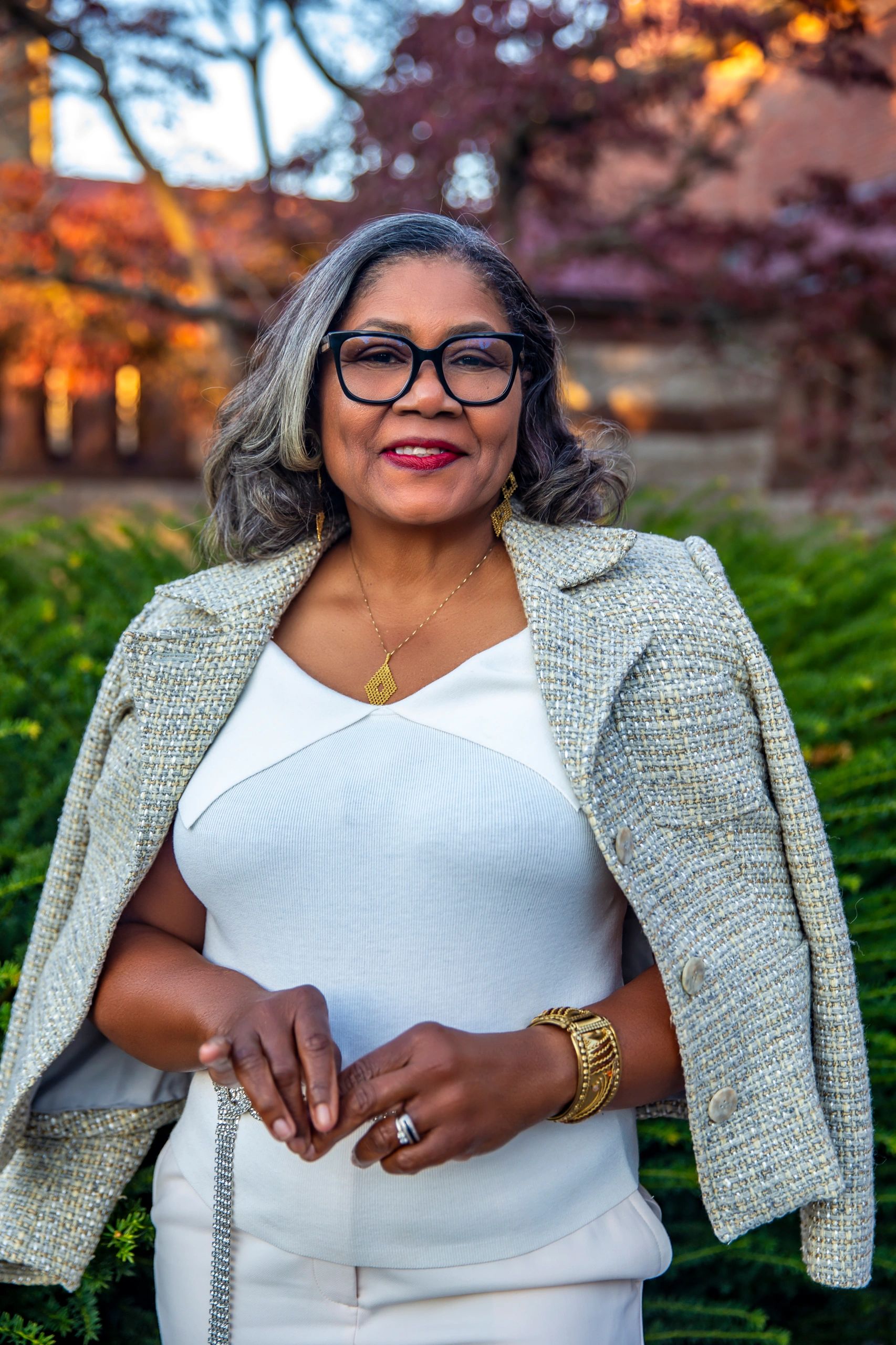 a woman in a white dress with a jacket draped over her clothes looks straight ahead