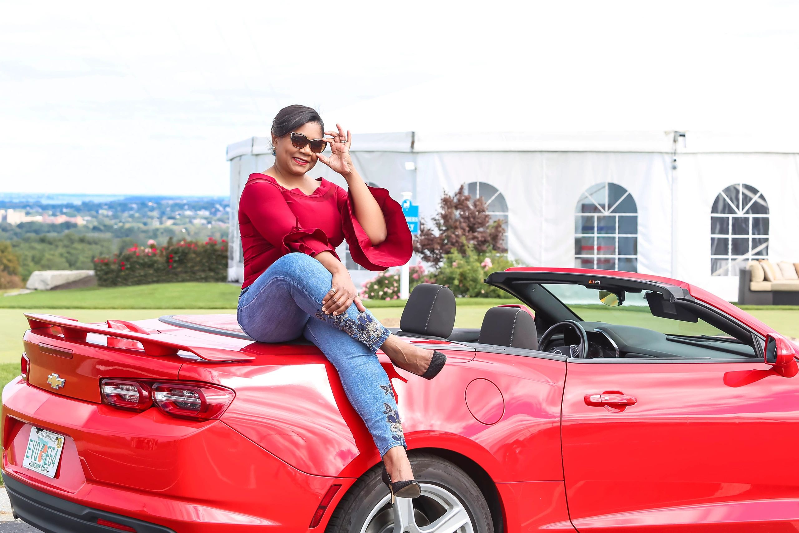 a woman sits on a raised platform posing for a photoshoot.