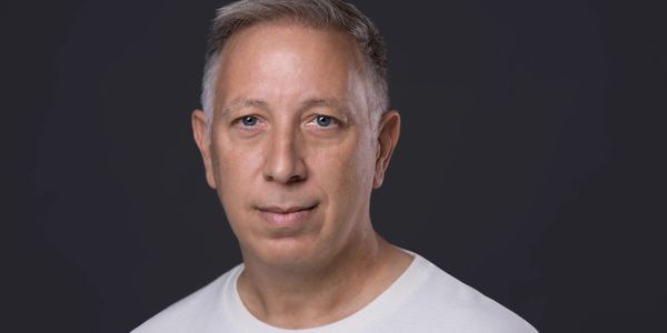 Portrait of a middle-aged man with gray hair and blue eyes wearing a white shirt.