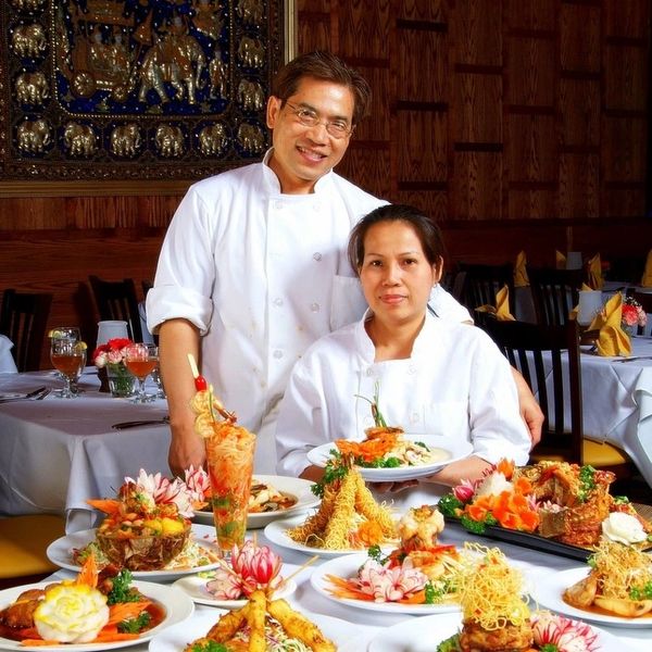 Two chefs presenting an array of beautifully plated gourmet dishes in a restaurant.