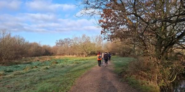 People walking along a dirt path in a natural park during autumn.