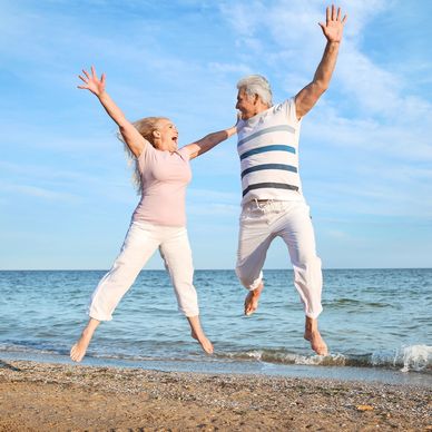two older adults jumping at the beach in Ponte Vedra Beach NIR treatment Redlight therapy