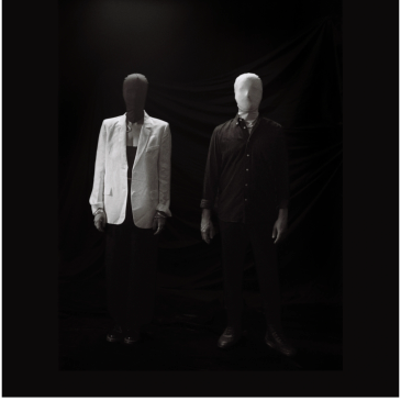 Two faceless mannequins dressed in contrasting black and white attire.