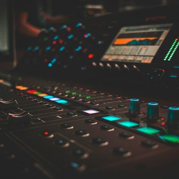 Close-up of a sound mixing console with illuminated buttons.
