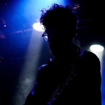 Silhouette of a person with glasses under stage lights.