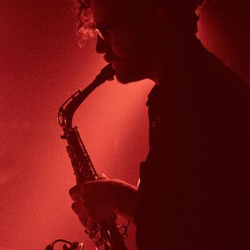 Silhouette of a man playing saxophone in red light.