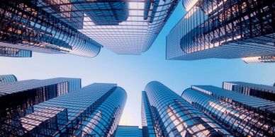 Looking up at tall, glass skyscrapers against a clear blue sky.