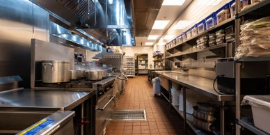 A clean, well-organized commercial kitchen with stainless steel equipment and cooking pots.